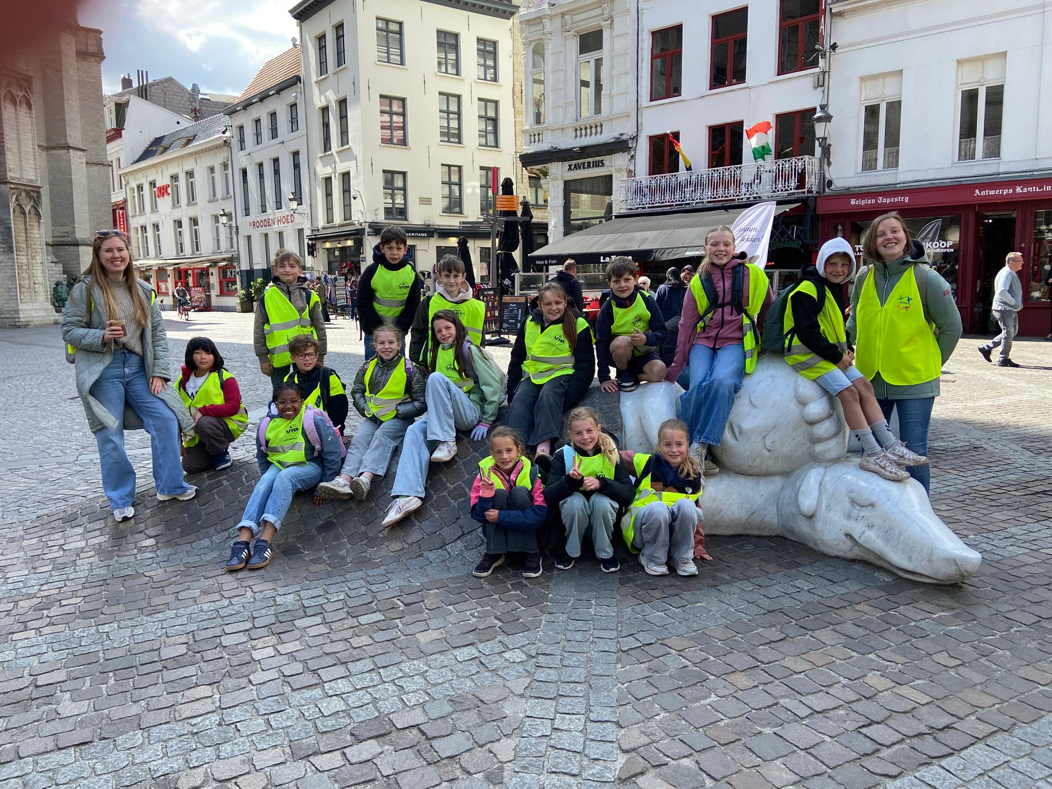 kinderen zitten op een standbeeld van Nello en Patrasche in Antwerpen